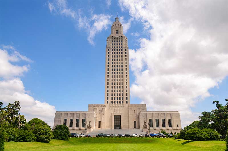 A photograph to represent Louisiana, featuring the capitol building rising up into a blue sky with fluffy clouds.