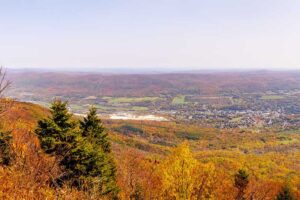 A photograph to represent Massachusetts, featuring a view from Mount Greylock, overlooking a golden valley dotted with dwellings.