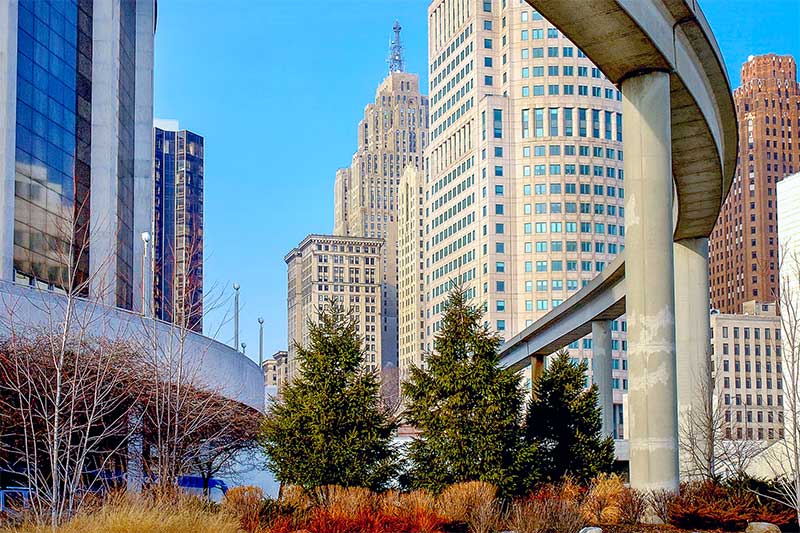 A photograph to represent Michigan, featuring a view of some of Detroit's skyscraper viewed from underneath an elevated pathway or roadway.