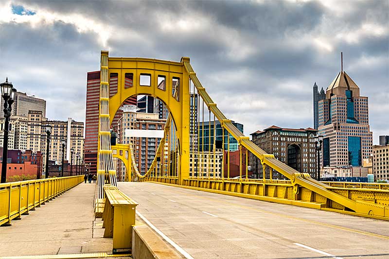 A photograph to represent Pennsylvania, featuring the roadway on a bright yellow bridge heading into a city.