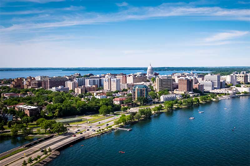 A photograph to represent Wisconsin, featuring Madison's capitol building, flanked on either side by deep blue water.