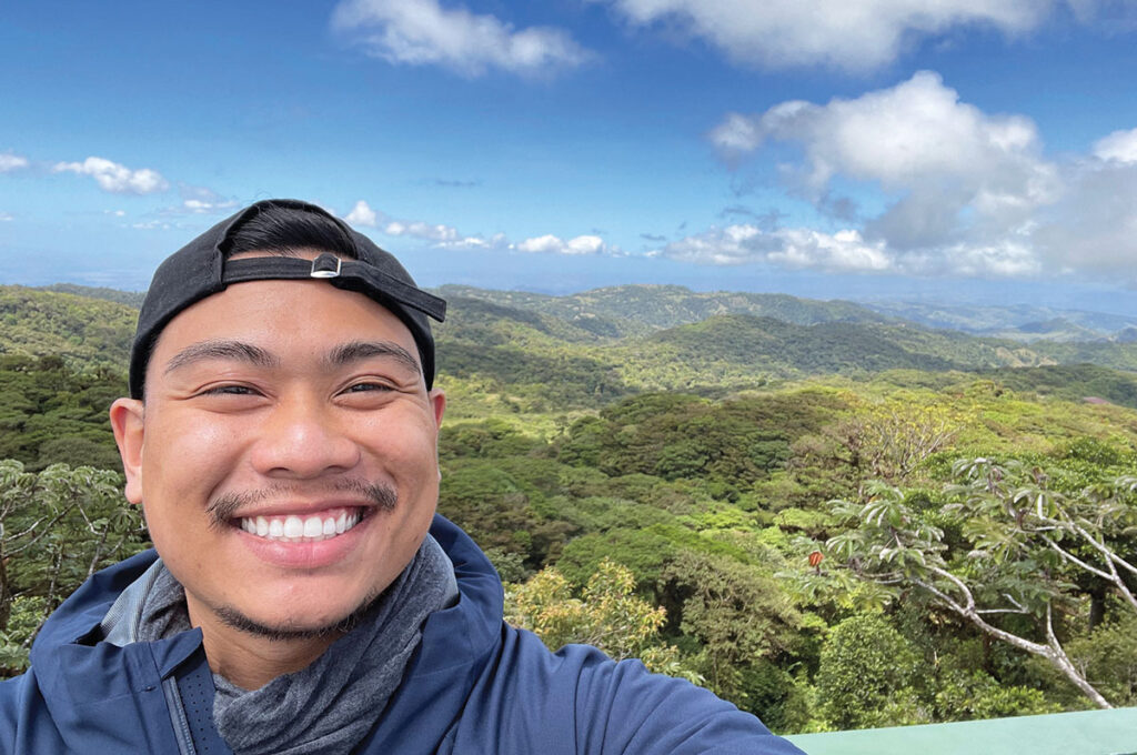 A selfie taken by current clinician Jovi Valarao, Registered Respiratory Therapist, smiling atop a tree-covered hill.